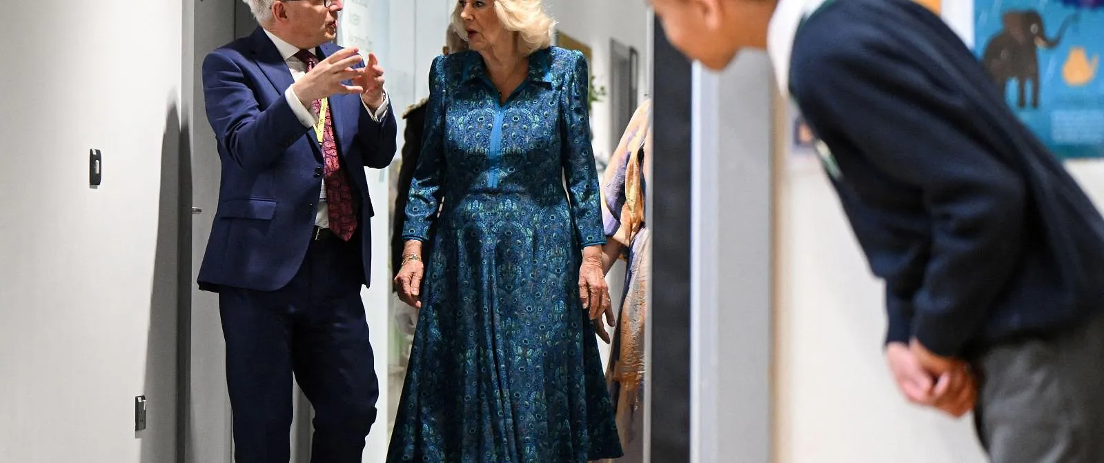 A pupil looks at Britain's Queen Camilla (C) arriving at the assembly hall of the Moreland Primary School, in London, on May 7, 2024, during a visit to open a new Coronation Library, the 50th in a series of special primary school libraries that have been transformed over the last twelve months with the help of the National Literacy Trust, to mark the Coronation. (Photo by JUSTIN TALLIS / POOL / AFP)